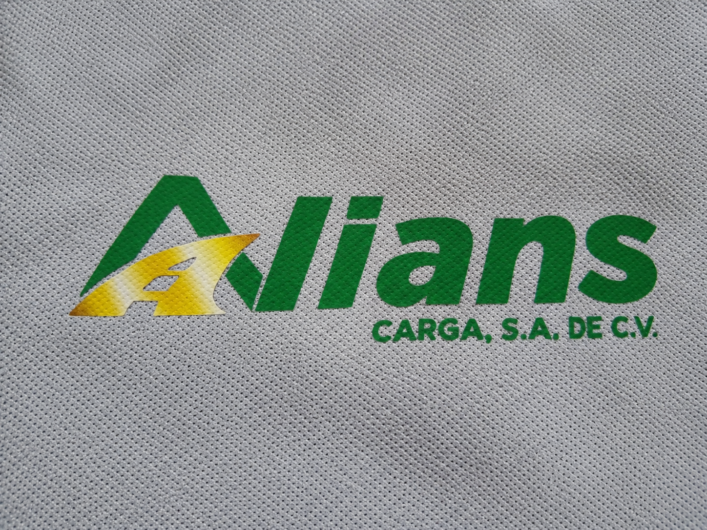 Detalle de estampado DTF Alians Carga sobre polo gris